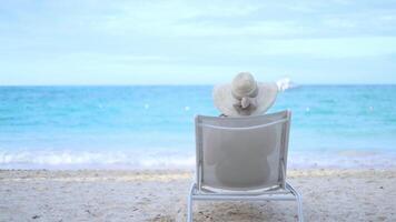 Relaxing by the beach with a wide-brimmed hat and gentle ocean waves in the background video