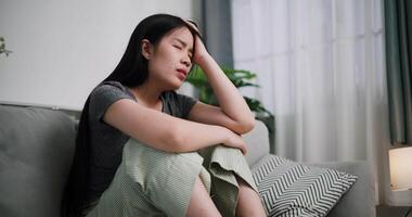 Stressed young woman sits alone on a sofa, thinking aimlessly, feeling worried about something. Life problems video