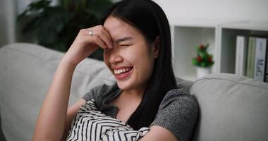 Handheld shot, Happy Asian woman sits smiling and laughing to herself as funny memories and thoughts come to mind. video