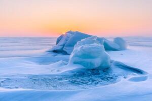 Winter landscape. A frozen surface of ice with snow intersected by many cracks. photo