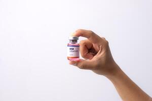 a hand holds a bottle of b12 vitamins in her clinic room. medical concepts photo