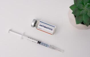 an antibiotic with a syringe and an ornamental plant in the upper corner. medical concept photo