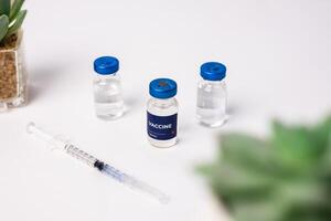 top view of some vaccines with ornamental plants on the table, inside the clinic room. health and medical concepts photo