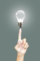 Finger pointing at an illuminated bulb, idea concept photo