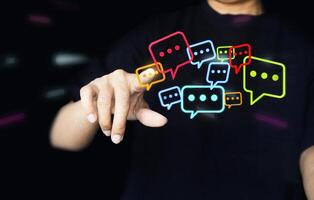 Touching with his fingers digital colorful speech bubbles talk icons. Minimal conversation or social media messages floating in front of businessman hand. photo