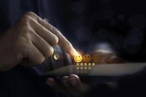 Hand using smartphone with popup happy smile face, five star icon for feedback review satisfaction service. photo