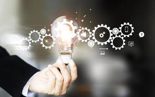 Hand holding light bulb and cog inside. Idea and imagination photo
