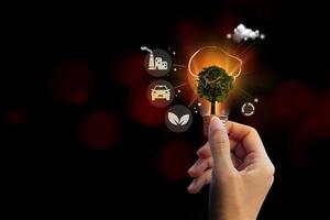 a hand holding a light bulb with a tree and icons photo