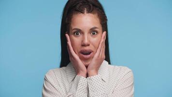 Surprised Woman With Hands on Face on Blue Background video