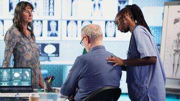 Girl physician uses precise techniques to examine a senior patient during a physical routine checkup, focusing on posture improvement and muscles pain in a well equipped facility. Camera B. video