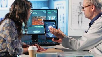 Meeting between doctor and patient to examine MRI scan showing a tumor, exploring treatment options, including immunotherapy, chemotherapy and preventative medicine. Risk factors. Camera B. video