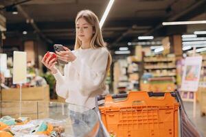 Customer using smartphone app choosing pomegranate in supermarket photo