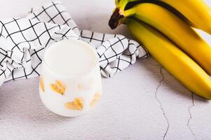Banana vegan alternative milk in glass and fruits on table photo