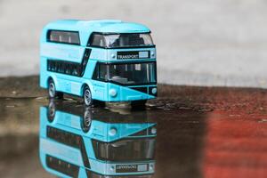 Close up photo of a blue children's toy double-decker bus on an abstract background
