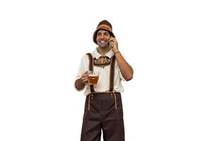Young bavarian man talking on cellphone while holding a beer glass in oktoberfest attire photo