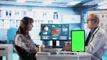Aged physician ensures disease prevention with isolated chroma key display, listening to patient with illness to create recovery plan. Medic recommending treatment on health insurance. Camera A. video