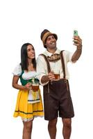 vertical Young bavarian couple taking a selfie with cellphone in Oktoberfest attire white background photo