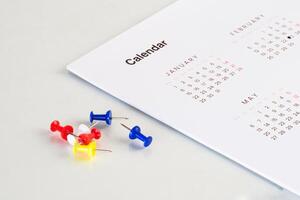 table with calendar sheet and bunch of pin photo
