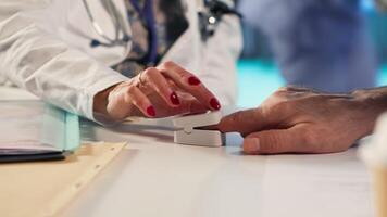 Female healthcare professional uses an oximeter to measure the oxygen levels for patient at check up, accurate medical advice for recovery. Monitoring pulse and saturation with tool. Camera B. video