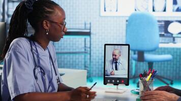 Nurse discussing with patients while on videocall with an expert, receiving professional diagnosis and different advice for recovery. Doctor supporting clients via internet conference. Camera B. video