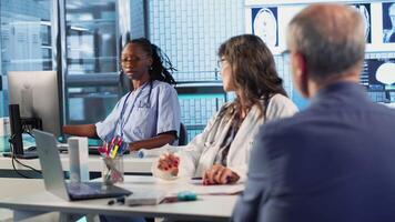 mayor hombre paciente reunión con su médico a discutir resultados en un oficina, utilizando avanzado herramientas a proporcionar diagnóstico informe. médico haciendo X rayo escaneos interpretación, profesional acercarse. cámara b. video