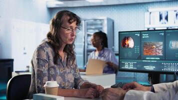 Senior healthcare medic sharing his expertise and interpreting the MRI scans results, offering advice and support to sick woman at checkup. Accurate diagnostics and patient care. Camera A. video