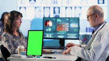 Old general practitioner consulting a female patient next to chroma key space, discussing about important medicine. Physician offers professional advice and suggestions for treatment. Camera B. video