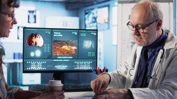 Specialist and old woman discuss x ray scan for preventive cancer medicine and health awareness. Cancer expert provides a geriatric patient with insights into tumor risks. Camera A. video