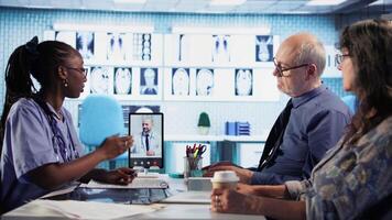African american nurse making a videocall with doctor to chat with patients, doing a remote check up and telemedicine concept. Skilled medical assistant asks opinion of a specialist. Camera A. video