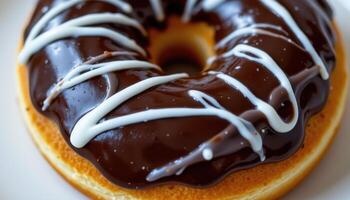 close up view of a donut with chocolate glaze and zigzag lines of white icing across the top. photo