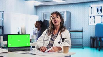 Experienced physician doing checkup routine with patient next to chroma key screen, discussing about medicine and wellness. Man using health insurance for consultation with medic. Camera A. video