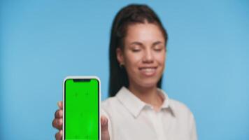 Woman showing smartphone with green screen close-up video