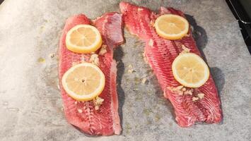 Raw African catfish fillets with lemon and garlic ready for baking photo