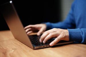 Hands typing on a laptop on a wooden table with a focus on the workspace atmosphere photo