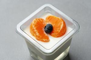 Creamy dessert topped with orange slices and a berry on a gray surface in a modern kitchen setting photo