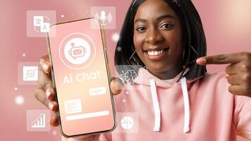 Young woman demonstrating AI chat application on smartphone against a pink background during a tech event photo