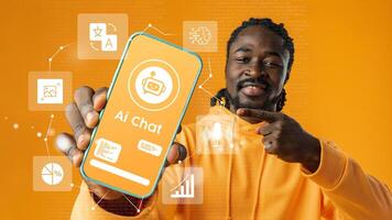Young man showcases AI chat application on smartphone with vibrant orange background in modern digital environment photo