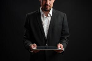 Business professional holds tablet in a dark setting while dressed in formal attire for corporate presentation photo