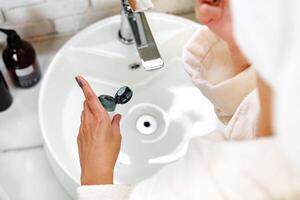 Person applying skincare product at a bathroom sink while preparing for a self-care routine photo