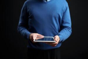 Person using a tablet while standing against a dark background during an indoor setting in a casual environment photo