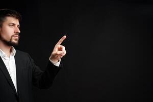 Man in a suit gestures confidently while speaking during a formal presentation in a dimly lit room photo