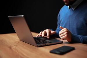 Professional man working on laptop at wooden desk during evening hours in modern office setting photo