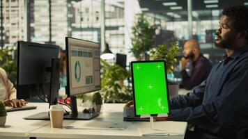 Close up of green screen tablet in front of employee checking progress done on project. Chroma key device next to office clerks reading data statistics on PC screen, camera B video