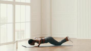 A woman works out at home, focusing on her push-up routine in a well-lit indoor space. She embodies a commitment to health and fitness, showcasing a strong athletic presence. video
