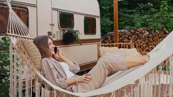 Woman relaxing in hammock, have phone call while enjoying camping video