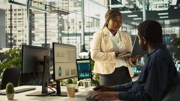 Manager in office ensuring worker hits key performance targets for revenue, profitability and operational efficiency. Corporate management executive board member talks with employee at work, camera B video