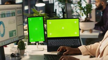 Mockup tablet and laptop in office used by employee working on company administrative tasks. Chroma key devices on desk used by worker reviewing business data metrics, camera A video