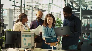 Coworkers in office doing brainstorming, reviewing financial charts, analyzing business performance metrics. Teamworking colleagues at work chatting, looking over data trends, camera B video