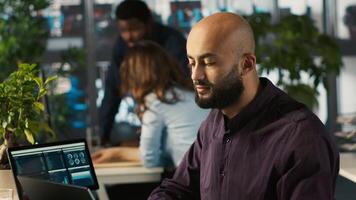 Happy man in office reviewing financial graphs, pleased after seeing good key performance indicators. Cheerful employee celebrating positive KPIs and data trends, camera A video