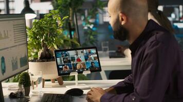 Worker in office talking with colleagues during internet videocall. Employee at work discussing with business partners during remote teleconference meeting, analyzing metrics, camera A video
